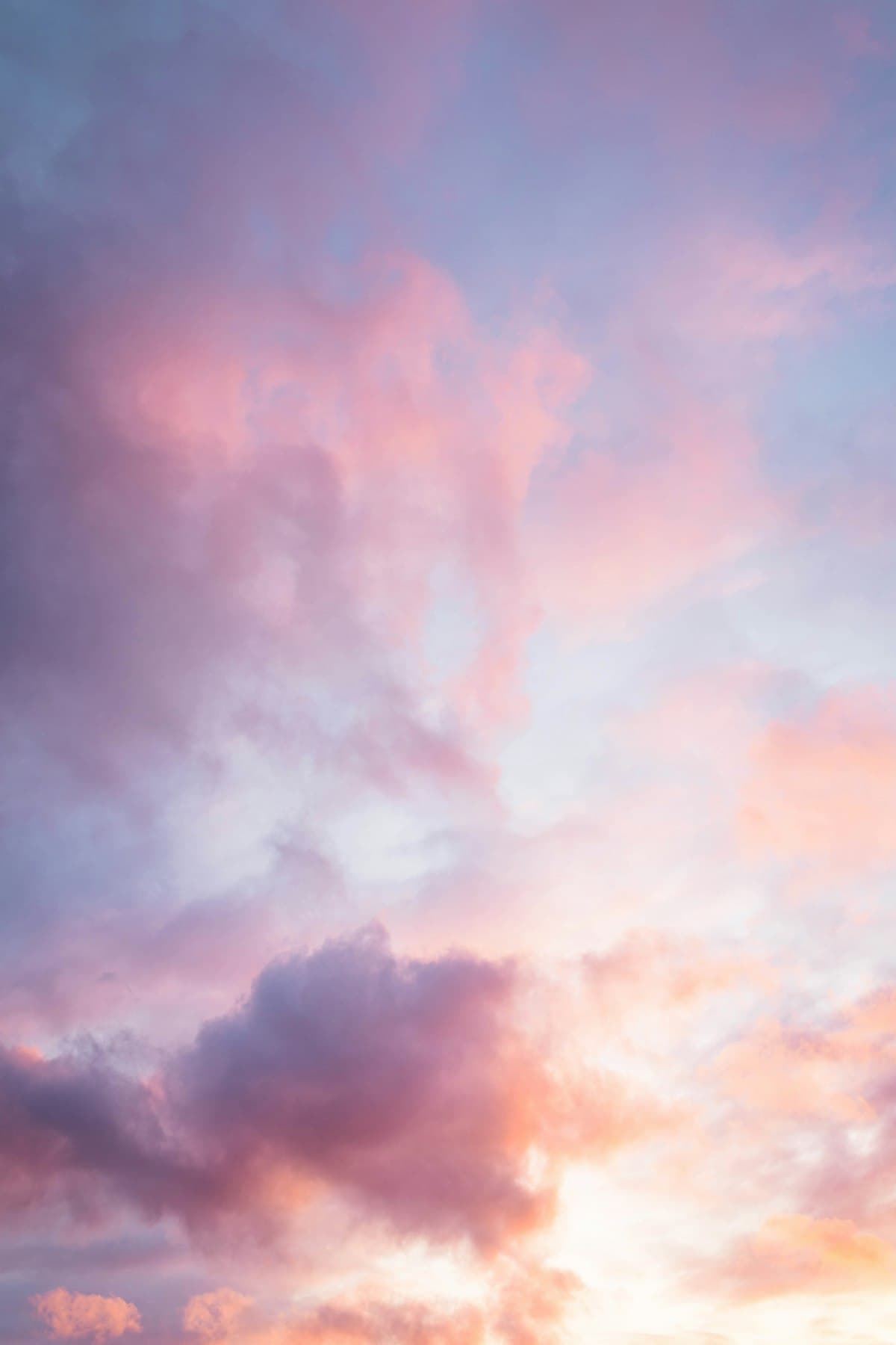 Soft pink and purple clouds drifting across a pale sky
